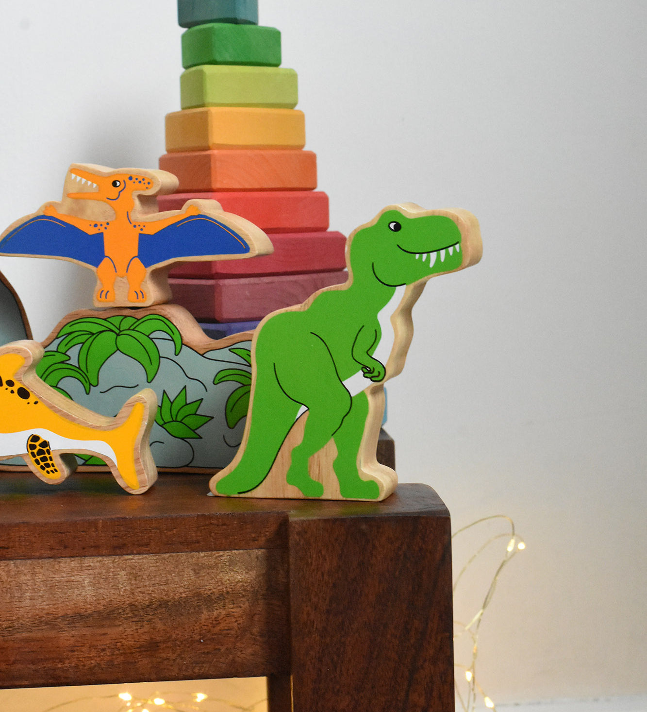 A Lanka Kade T Rex Dinosaur wooden toy figure placed on a small wooden table. These wooden toy figures are part of a huge range of Lanka Kade fair trade, wooden toys available here at Babipur.