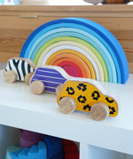 Lanka Kade wooden animal printed cars next to a Grimms rainbow on a shelf. Features a leopard, snail and zebra printed wooden car. 