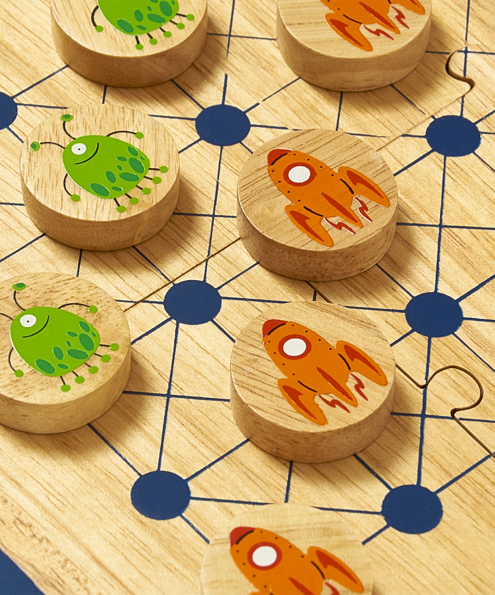 A close up of the Lanka Kade cosmic wooden board game showing the orange rocket ship and alien design on the circular counters and board detail
