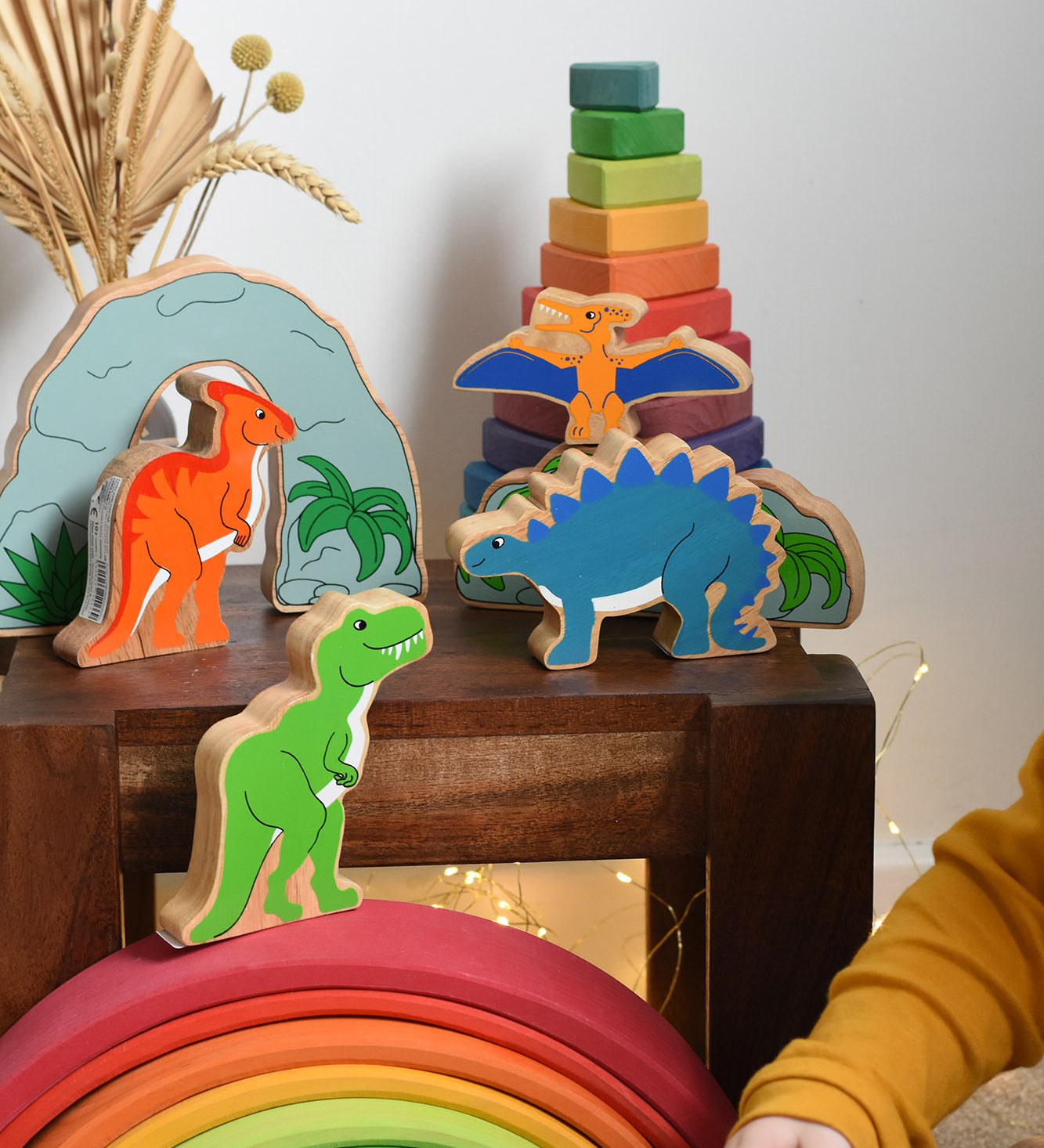 A collection of wooden dinosaurs from Lanka Kadeplaced on a small wooden table. These wooden toy figures are part of a huge range of Lanka Kade fair trade, wooden toys available here at Babipur.
