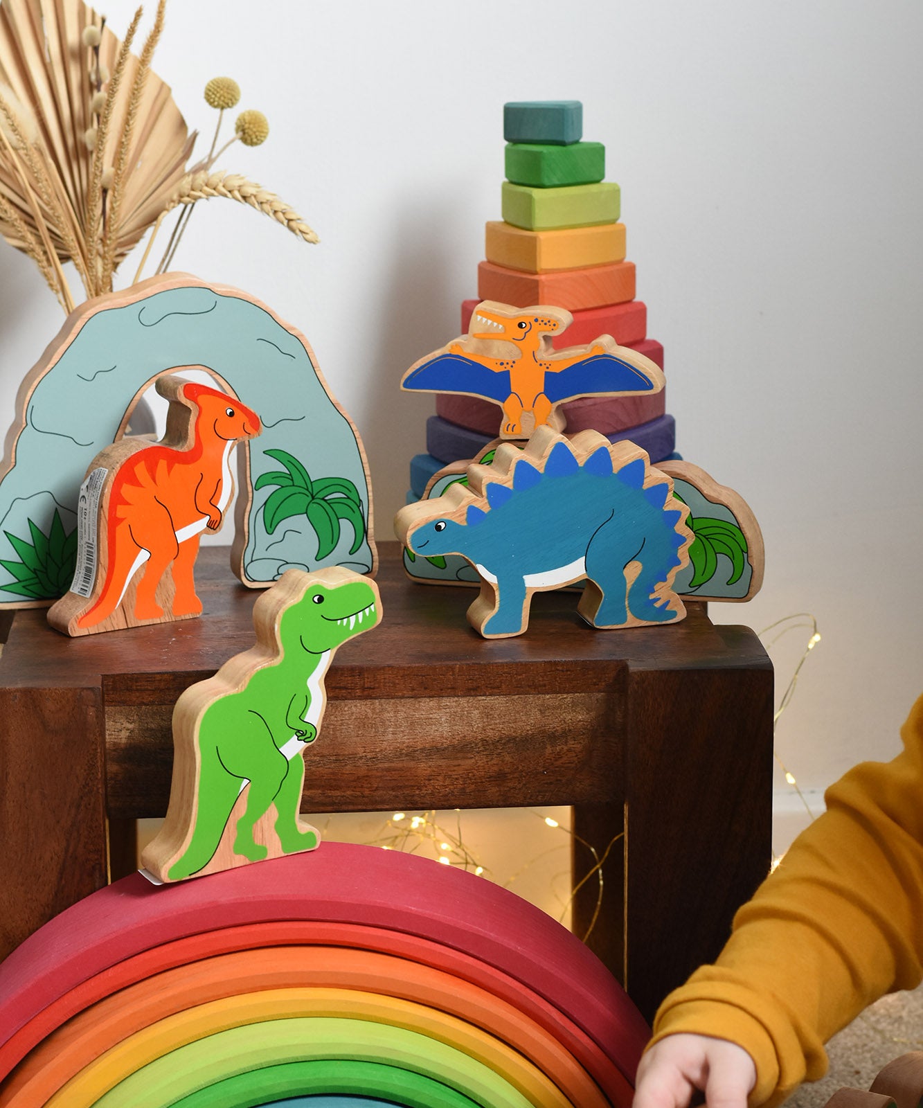 A collection of wooden dinosaurs from Lanka Kadeplaced on a small wooden table. These wooden toy figures are part of a huge range of Lanka Kade fair trade, wooden toys available here at Babipur.
