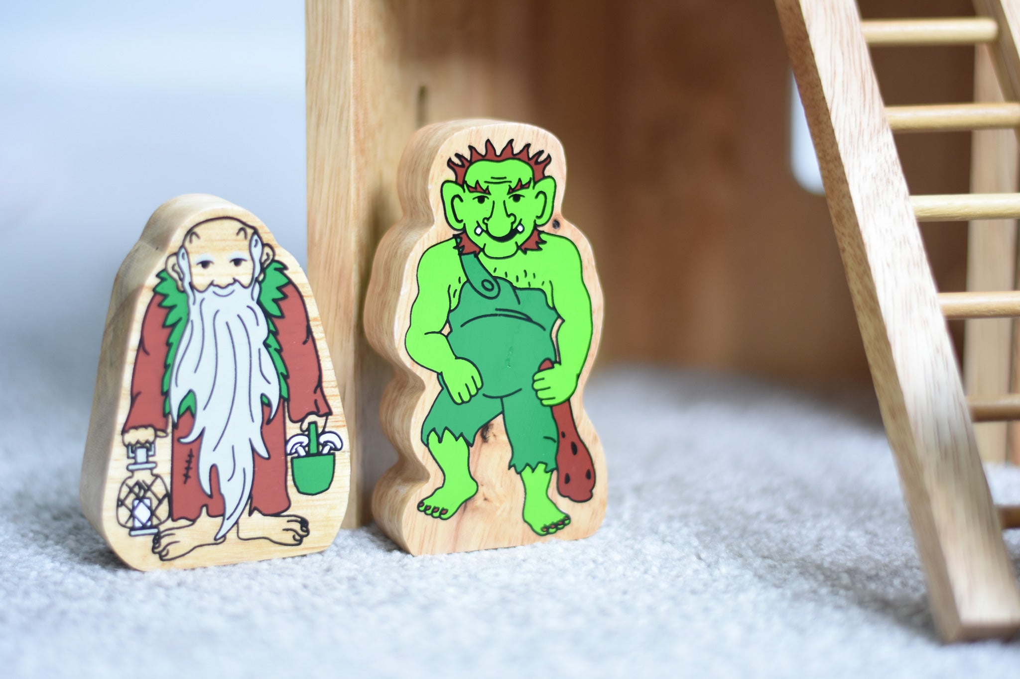Lanka Kade hermit and green troll wooden toy figures placed on a carpeted surface.