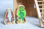 Lanka Kade hermit and green troll wooden toy figures placed on a carpeted surface.