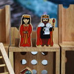 A close up of a King and Queen figure standing on the entrance gate of the Lanka Kade wooden toy castle. 