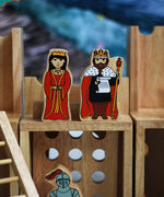 A close up of a King and Queen figure standing on the entrance gate of the Lanka Kade wooden toy castle. 