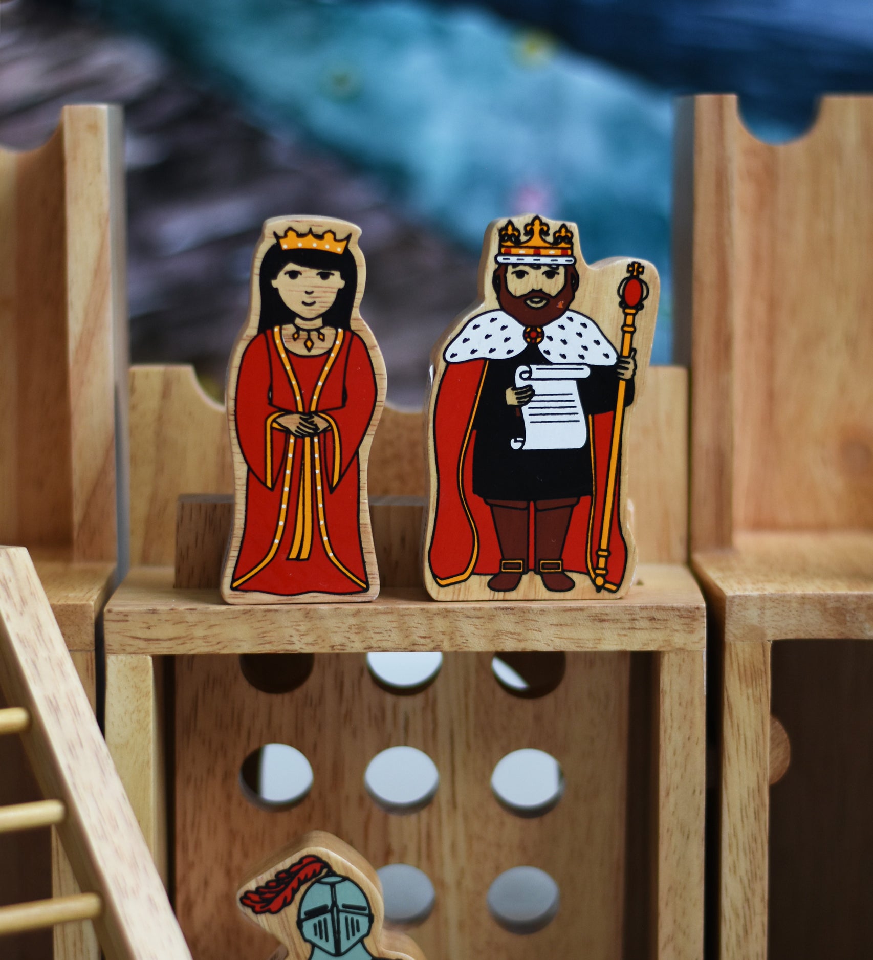 A close up of a King and Queen figure standing on the entrance gate of the Lanka Kade wooden toy castle. 