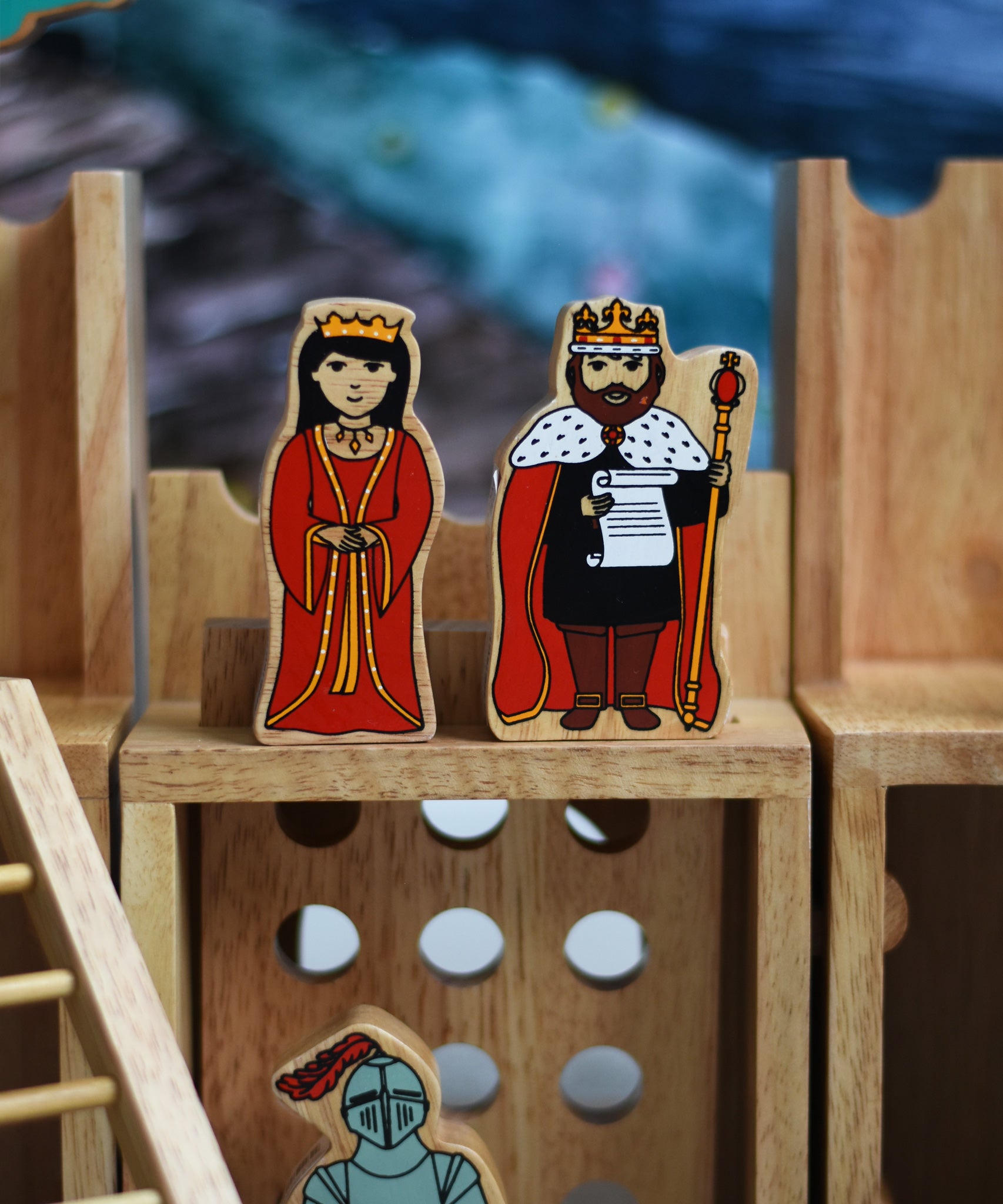 A close up of a King and Queen figure standing on the entrance gate of the Lanka Kade wooden toy castle. 
