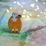 A Lanka Kade Wooden Yellow and White Vulture Toy placed on a Wonderie play cloth with fairy lights in the background. These wooden toy figures are part of a huge range of Lanka Kade fair trade, wooden toys available here at Babipur.