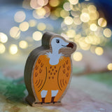 A Lanka Kade Wooden Yellow and White Vulture Toy placed on a Wonderie play cloth with fairy lights in the background. These wooden toy figures are part of a huge range of Lanka Kade fair trade, wooden toys available here at Babipur.