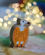 A Lanka Kade Wooden Yellow and White Vulture Toy placed on a Wonderie play cloth with fairy lights in the background. These wooden toy figures are part of a huge range of Lanka Kade fair trade, wooden toys available here at Babipur.