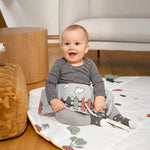 A smiling baby holding the Lassig Baby Touch & Feel soft toy book.