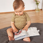 A little baby touching the Lassig Baby Touch & Feel soft toy book.
