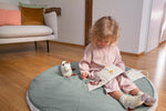 A little girl reading the Lassig Baby Touch & Feel soft toy book.