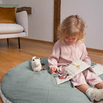 A little girl reading the Lassig Baby Touch & Feel soft toy book.