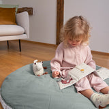 A little girl reading the Lassig Baby Touch & Feel soft toy book.