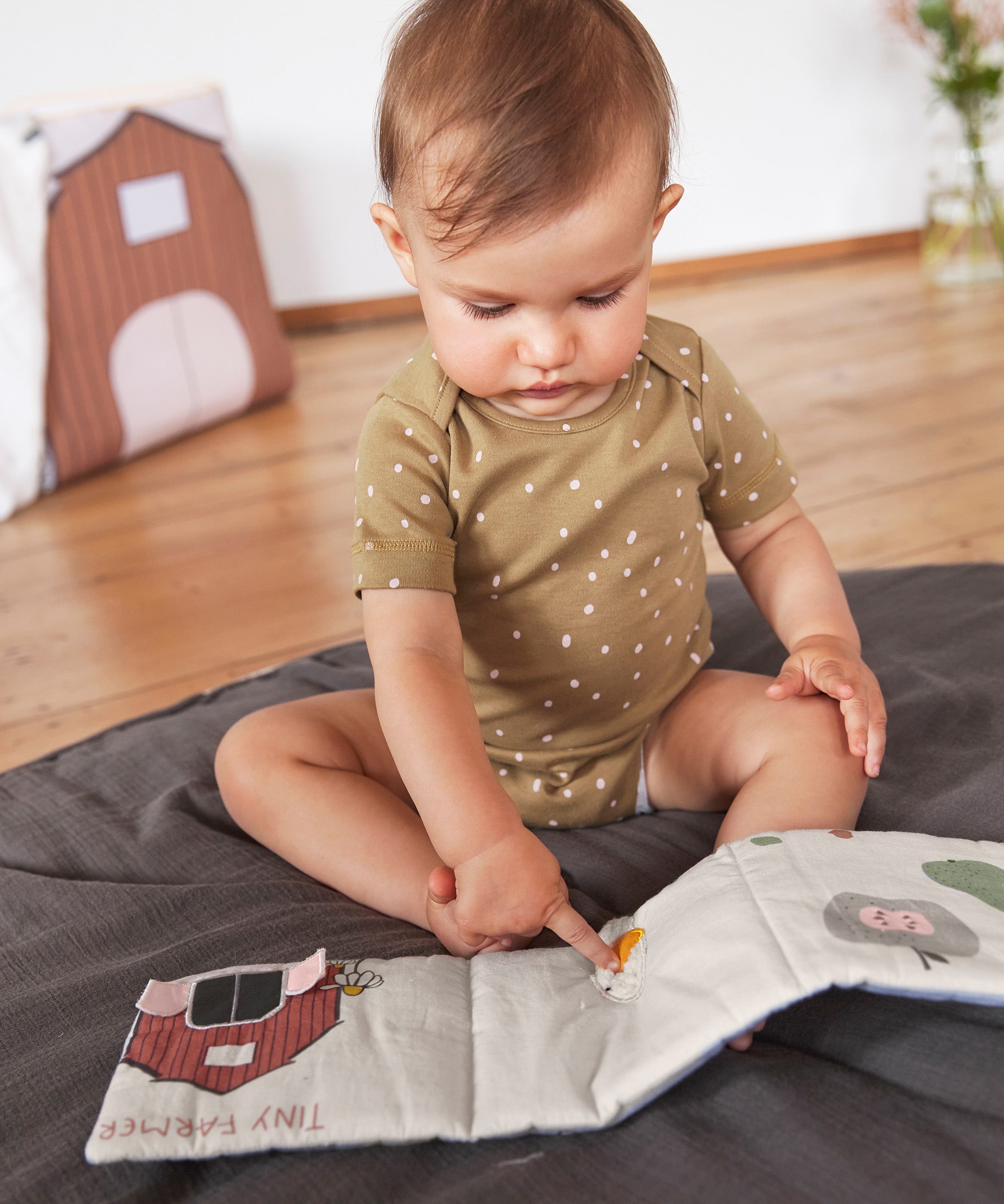 A littler baby touching the Lassig Baby Touch & Feel soft toy book.