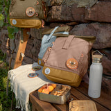 The Lassig Mini Rolltop Backpack in a Nature Hazelnut colour placed on a bench outdoors. Other colours of the bag can be seen in the background. This children's bag is part of a wide range of backpacks and accessories available at Babipur. 