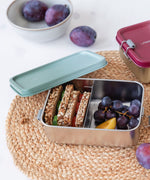 A Lassig Stainless Steel Lunchbox in the Unique Olive Green colour. The divided lunchbox is shown filled with food.