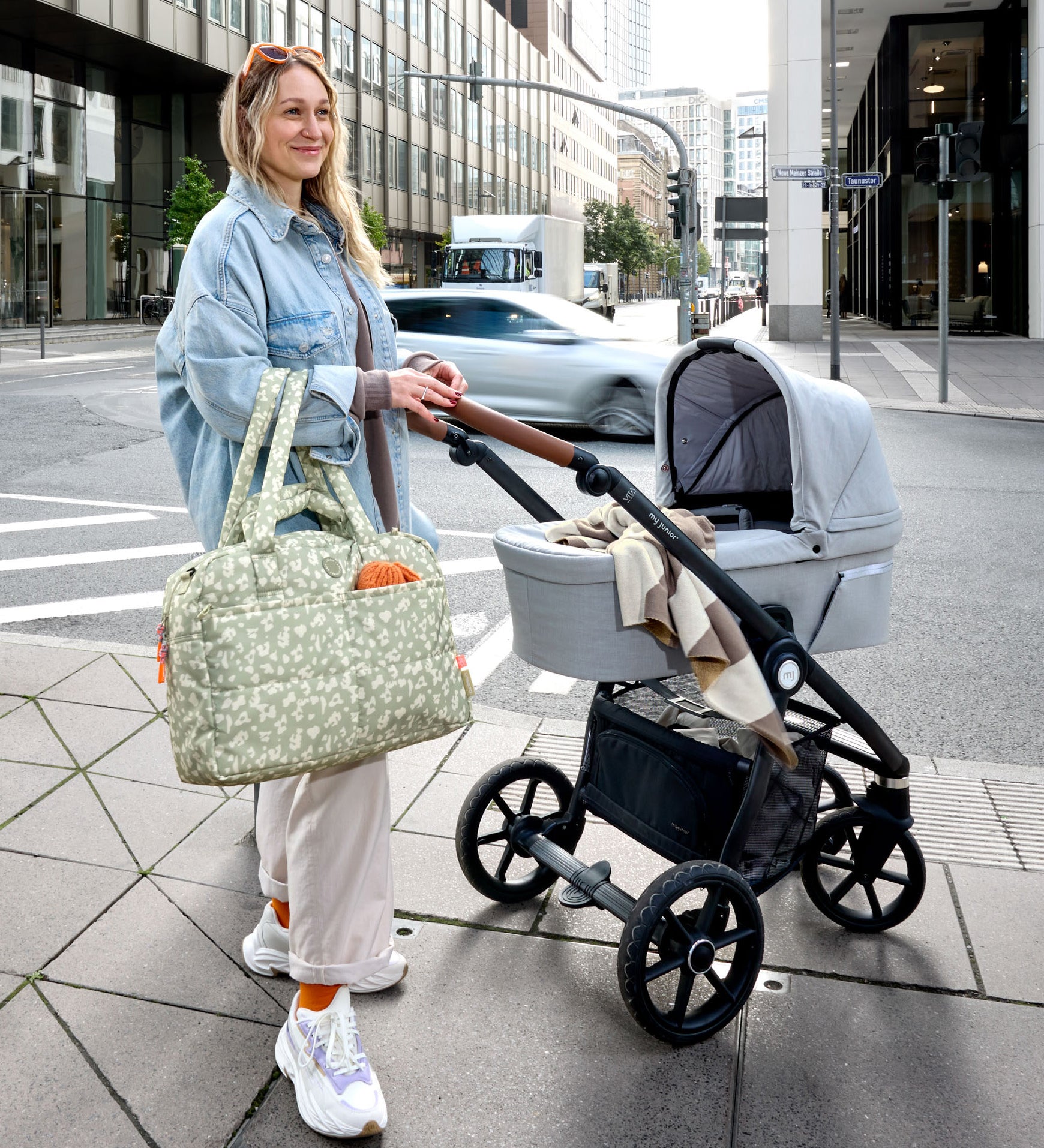 A woman with a pram and the Lassig every day change nappy bag in light khaki.