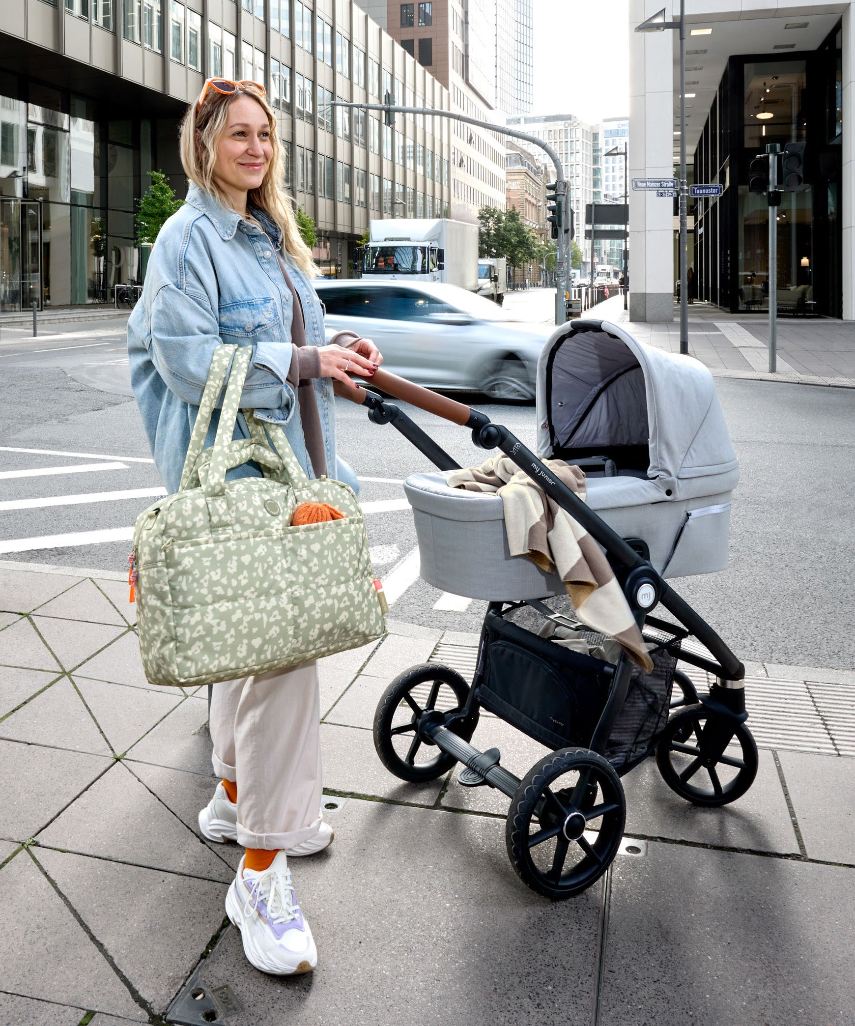 A woman with a pram and the Lassig every day change nappy bag in light khaki.