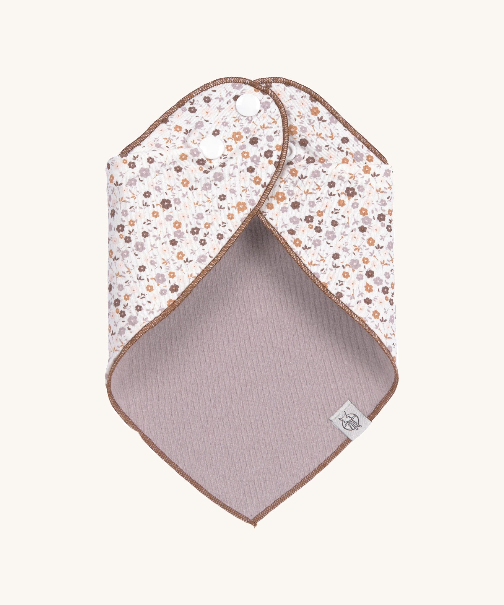The Lassig floral dribble bib for babies, fastened with poppers at the neck. 