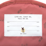 A closeup of the 'pass-me-on' name label inside the Lassig Kids mini backpack, with multiple spaces for kids to hand the bag down to younger siblings