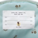 A closeup of the 'pass-me-on' name label inside the Lassig Kids mini backpack, with multiple spaces for kids to hand the bag down to younger siblings. 
