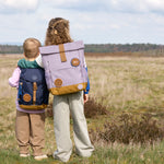Two children wearing Lassig kids backpacks in a field. 