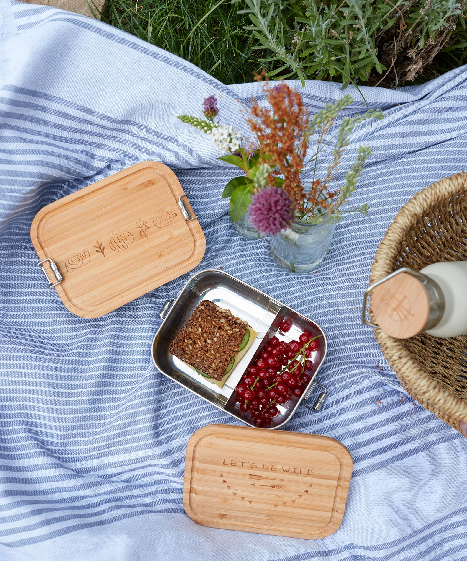 The Lassig Stainless Steel Bamboo Lunchbox with a Garden Explorer design shown open and filled with food. This stainless steel lunchbox is part of a wide range of reusable food containers available at Babipur. 