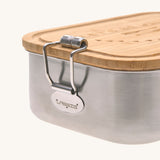 A close up of the clasp latch closure on the side of the Lassig Stainless Steel Bamboo Lunchbox with an Adventure design. The words let's be wild are written on the bamboo lid. This children's divided lunchbox is part of a wide range of food storage solutions available at Babipur.