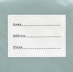 The inside label of the Lassig tiny kids backpack in grey raccoon, with space to write the child's name, address, and phone number. 