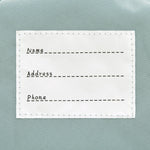 The inside label of the Lassig tiny kids backpack in grey raccoon, with space to write the child's name, address, and phone number. 