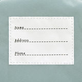 The inside label of the Lassig tiny kids backpack in grey raccoon, with space to write the child's name, address, and phone number. 