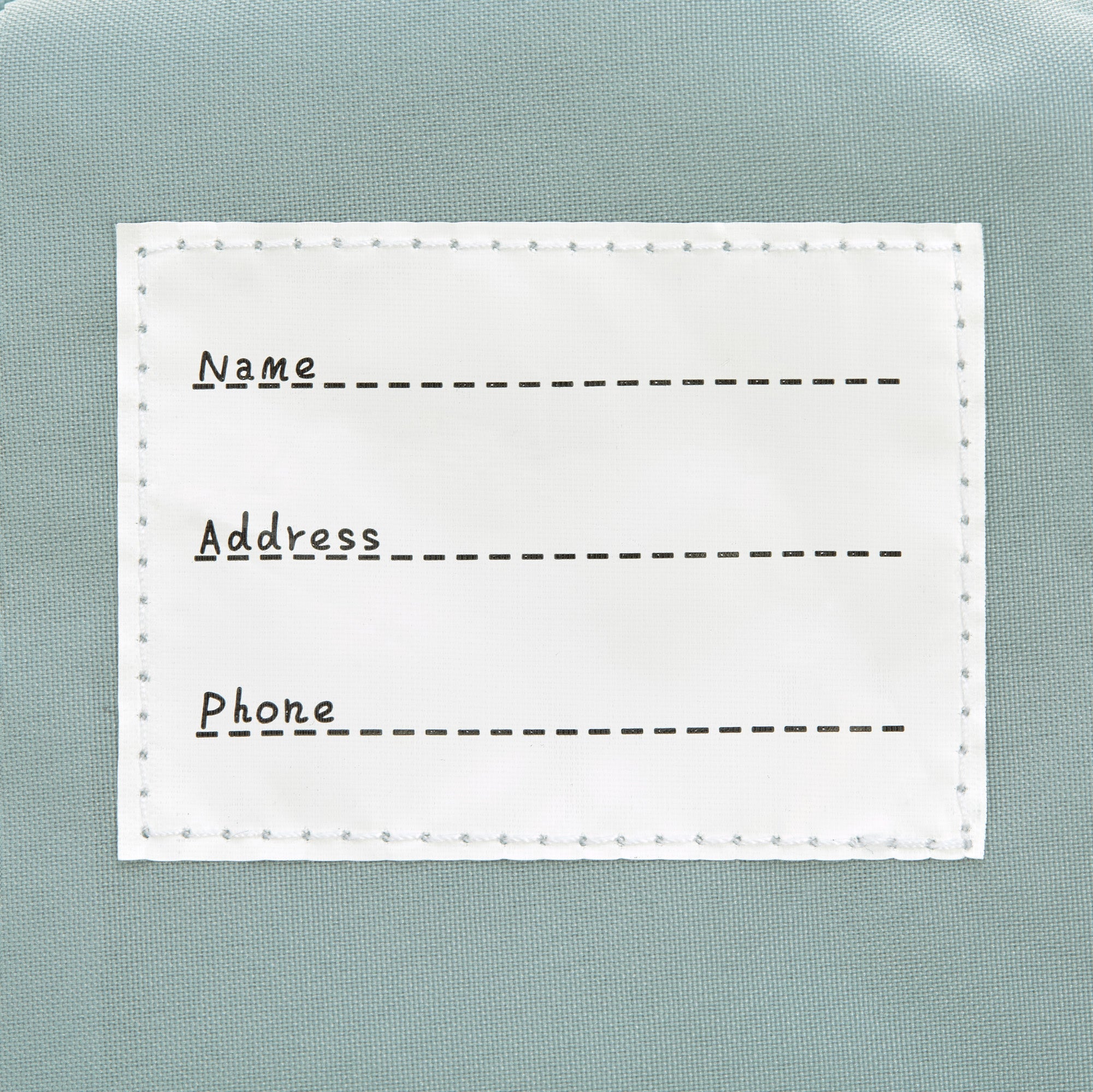 The inside label of the Lassig tiny kids backpack in grey raccoon, with space to write the child's name, address, and phone number. 
