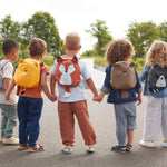 A group of children holding hands, all wearing different 'About Friends' tiny backpacks from Lassig with different animals. 