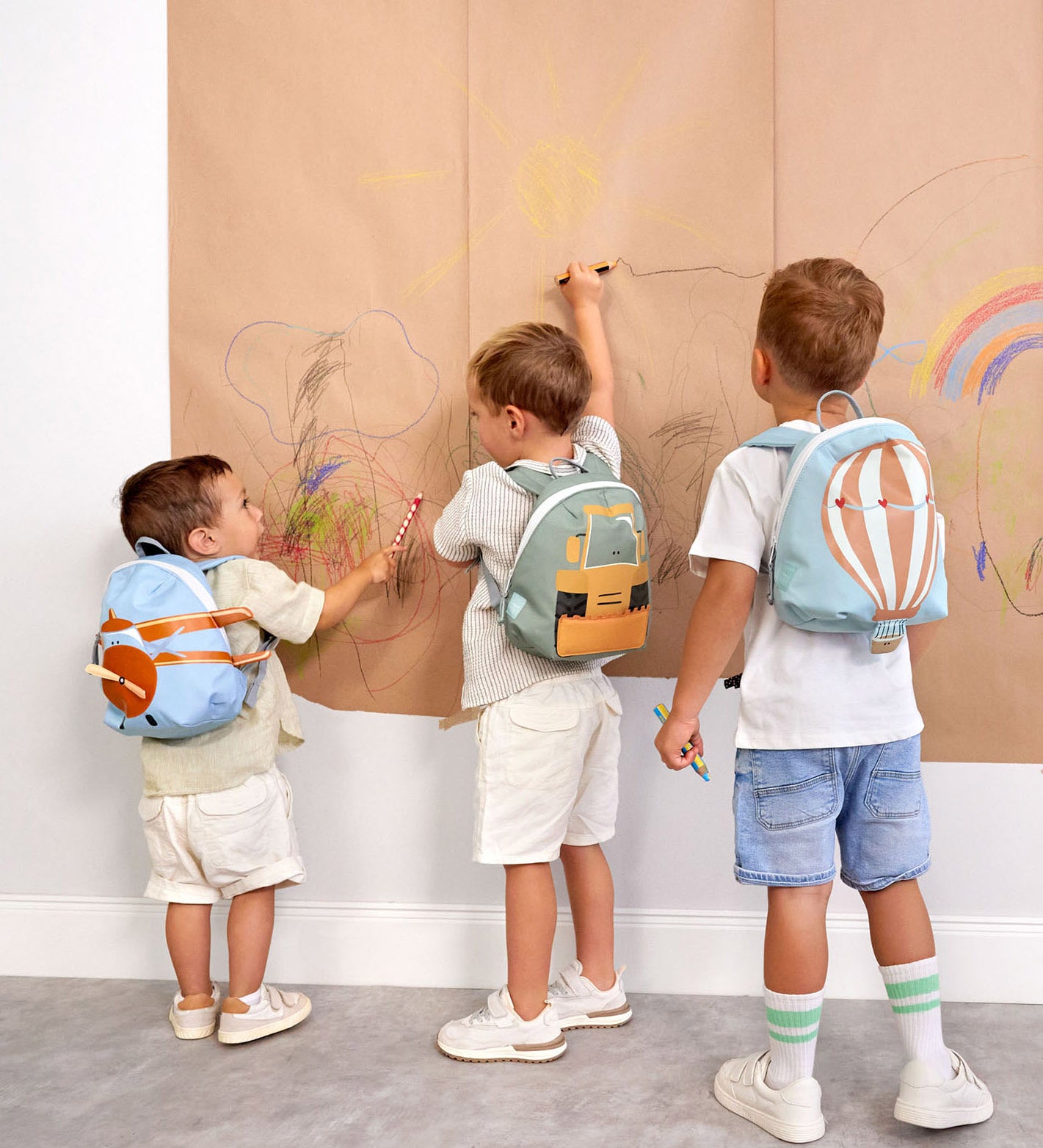 A group of kids wearing the aeroplane, digger and balloon character tiny Lassig backpacks.