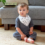 A baby wearing the Lassig organic cotton bandana bib, in white with grey triangles.