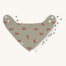Two Lassig organic cotton bandana bibs, one in green with little foxes printed all over, and one in white with grey triangles.