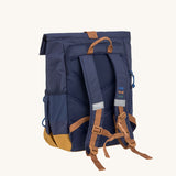 The back of the Lassig Medium Rolltop Backpack in a Little Gang Navy colour design. The children's bag has a brown coloured chest strap These roll top bags are available in different colours and sizes at Babipur.
