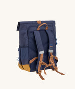 The back of the Lassig Medium Rolltop Backpack in a Little Gang Navy colour design. The children's bag has a brown coloured chest strap These roll top bags are available in different colours and sizes at Babipur.