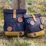 Lassig Medium Rolltop Backpack in a Little Gang Navy colour design shown next to a mini size. These roll top bags are available in different colours and sizes at Babipur.