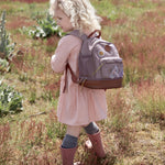 Little girl in a field wearing the Lassig dragonfly mini kids backpack.