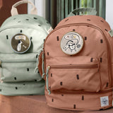 Lassig kids mini party caramel and olive pattern backpacks outside on a step. Features padded shoulder straps, mesh side pockets, a handy loop handle on the top and 3 zipped compartments. 