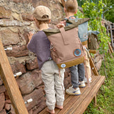A child wearing the Lassig Mini Rolltop Backpack in a Nature Hazelnut colour. This children's bag is part of a wide range of backpacks and accessories available at Babipur. 
