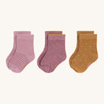 The Lassig 3-pack of organic cotton baby socks, one pair is light pink with darker pink stripes, another is in a darker pink with mustard yellow trims on the cuffs, and one is mustard yellow with light pink dots.