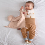 A baby playing with the Lassig organic cotton muslin comforter.