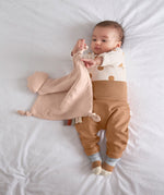 A baby playing with the Lassig organic cotton muslin comforter.