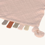 A closeup of the little tags on the bottom of the Lassig pink cloud organic cotton muslin comforter. 