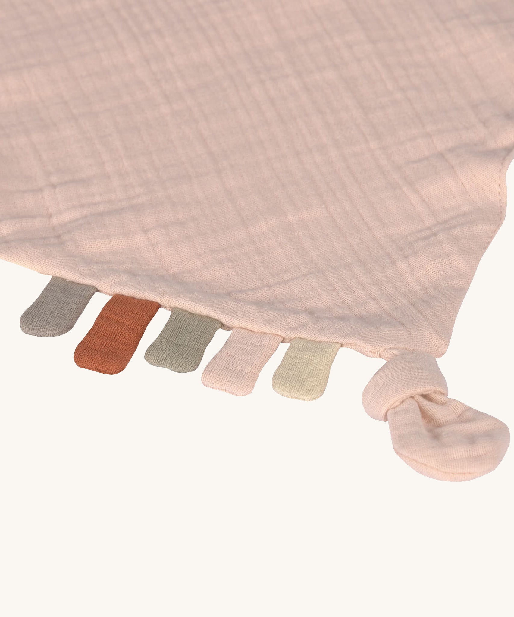 A closeup of the little tags on the bottom of the Lassig pink cloud organic cotton muslin comforter. 