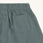 A closeup of the Lassig GOTS organic cotton muslin trousers in petrol green.